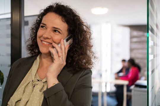 Professional woman on phone call in modern office corridor