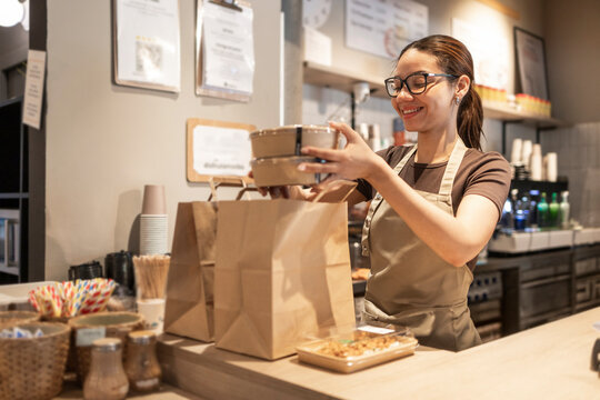 Woman at cafe counter prepares a takeout order