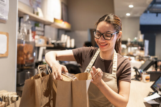 Smiling cafe worker preparing takeout orders