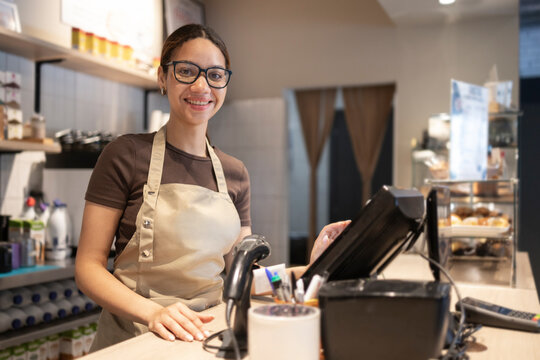 Smiling barista working at a cafe checkout counter