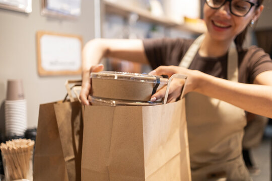Woman packing food in a paper bag at a cafe counter