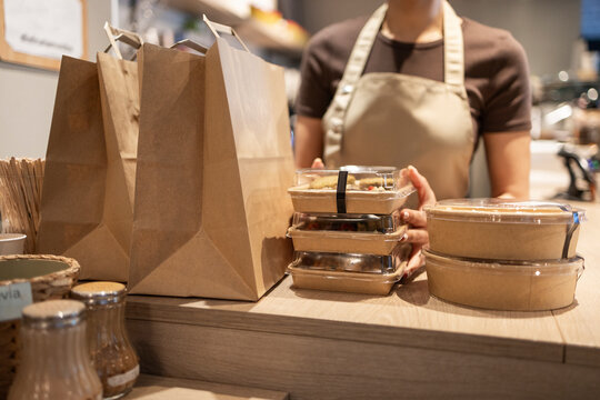 Cafe worker arranging takeaway food and bags