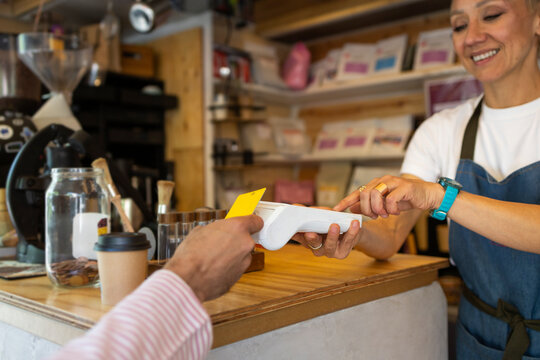 Customer tapping card for takeaway coffee at kiosk counter
