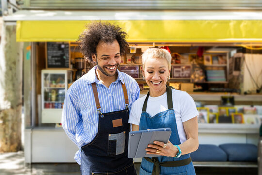 Baristas using tablet at outdoor coffee kiosk small business