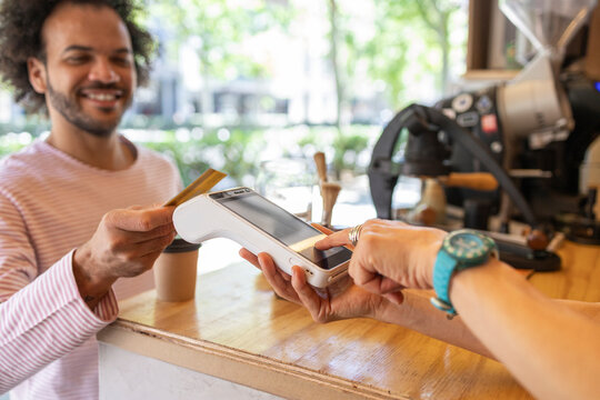 Customer paying by card at a small coffee kiosk counter