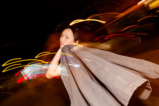 Asian woman in night street with motion blur light trails