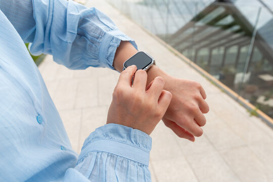 Young Gen Z checking smartwatch outdoors in modern city