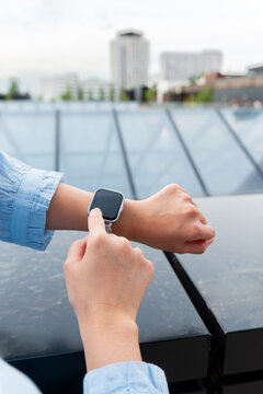 Gen Z using smartwatch on rooftop with city skyline