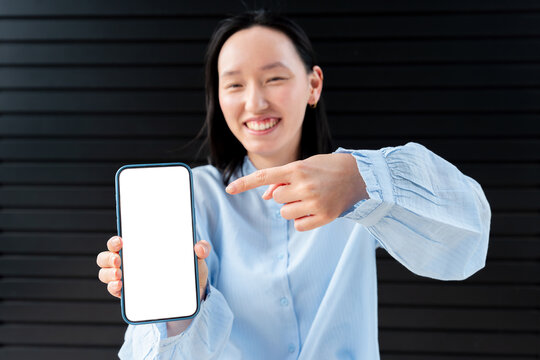 Smiling Gen Z Asian woman showing phone with blank screen