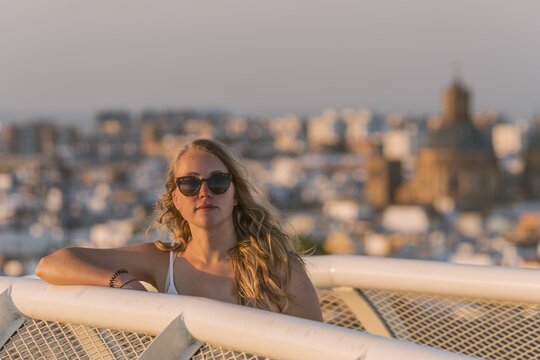 Young woman in sunglasses looks into the camera, Plaza de la Encarnacion, behind houses, Seville, Andalusia, Spain