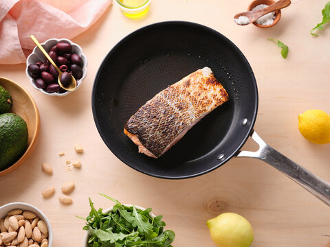Pan-seared salmon filet on a skillet surrounded by fresh ingredients