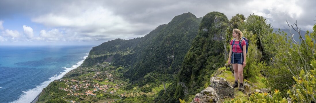 Hiker on the ridge of Pico do Alto, view of coast and sea with village Arco de Sao Jorge, Madeira, Portugal