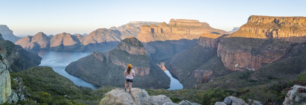 Hiker enjoying sunset at Blyde River Canyon with Three Rondawels peak, view of canyon with Blyde River and table mountains in the evening light, Canyon landscape, Panorama Route, Mpumalanga, South Africa