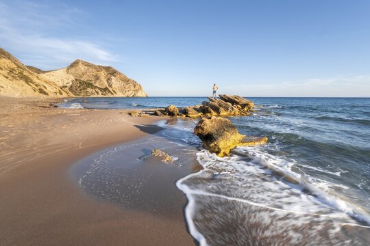 Man standing on a rock, coast at Paradise Beach, beach and turquoise sea, Kos, Dodecanese, Greece