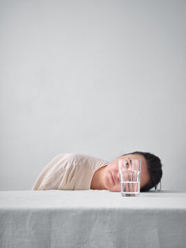 Woman resting head on table near glass of water