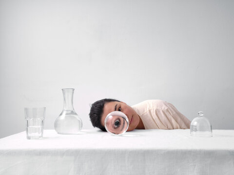 Woman gazing through crystal ball on white table