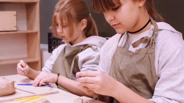 Craft hobby. Ceramic workshop. Two creative girls molding handmade raw using color tool in pottery artisan art professional studio.