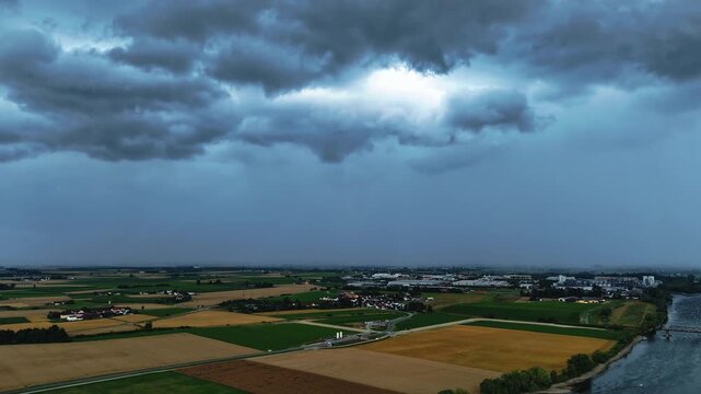 Die Wolken sind dunkel und bedrohlich. Sie ziehen &uuml;ber das Feld und die Stadt Straubing. Die Landschaft zeigt verschiedene Felder und H&auml;user.