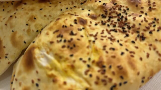 Bread pastry food, golden baked flatbread with sesame seeds served on a white cloth in a rustic kitchen setting