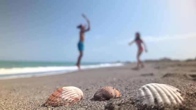 Two people enjoying playful paddle game on a sunny beach with seashells, embodying carefree fun and summer vacation freedom.