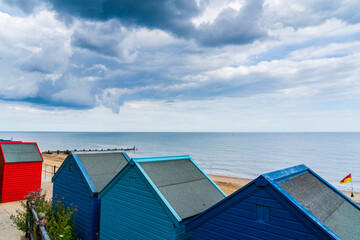 The tops of colourful beach huts taken during the Summer season with storm clouds above, representative of a common British holiday