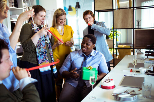 Coworkers celebrating a birthday with a gift in a modern office