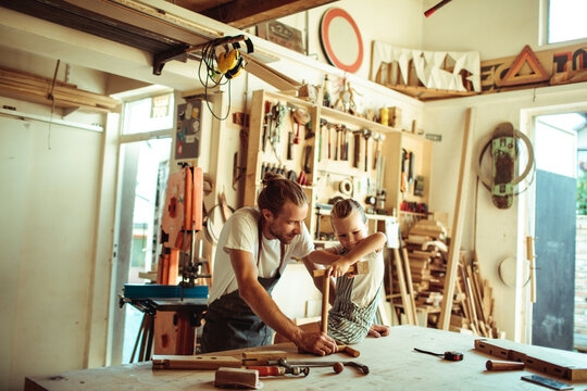Father teaching daughter woodworking in home workshop