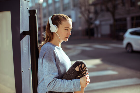 Young woman stretching with headphones on city street