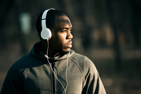 Focused athlete wearing headphones in park at dawn