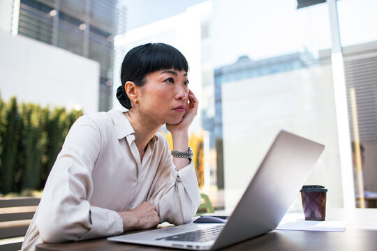Focused businesswoman working on laptop outdoors in city