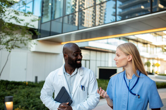 Doctor and nurse discussing care outside modern hospital