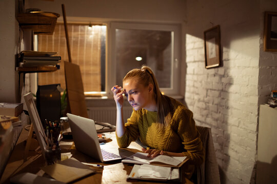 Young woman working late on laptop at home office