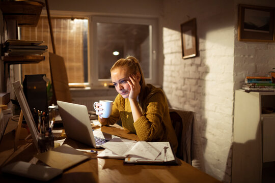 Young woman working late at home office desk at night