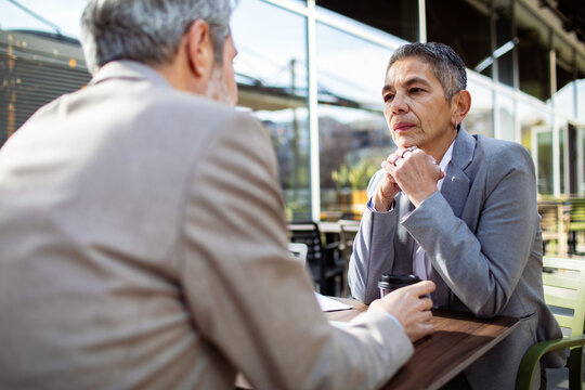 Senior business colleagues discussing strategy at outdoor cafe