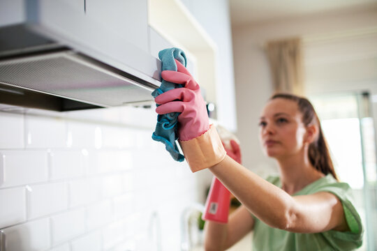 Woman cleaning kitchen range hood at home