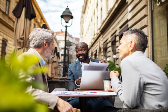 Colleagues discussing business strategy at outdoor city cafe