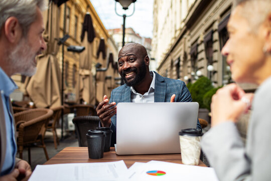 Smiling businessman meeting with colleagues at outdoor cafe
