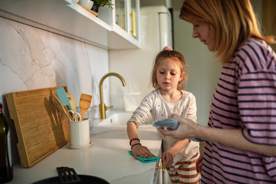 Mother and daughter cleaning kitchen counter at home