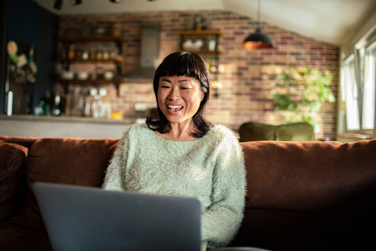Smiling woman video chatting on laptop at home