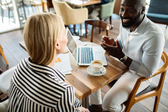 Two colleagues discussing a project over coffee in a cafe