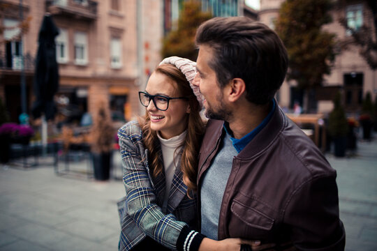 Young couple laughing together on city street in autumn
