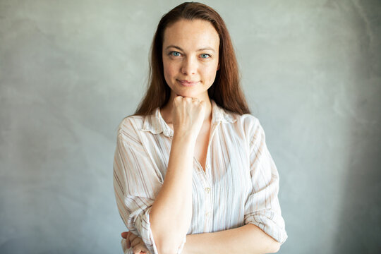 Confident young woman portrait against gray studio wall