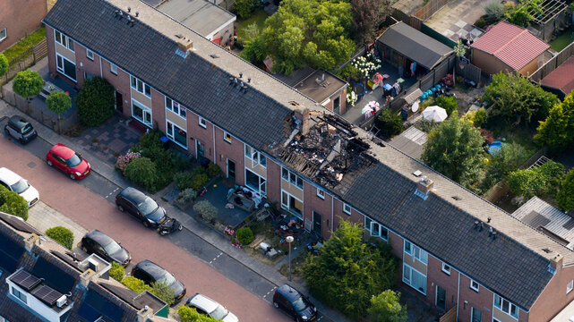 Aerial view of the aftermath of a residential house fire caused by a lightning strike, showing severe roof damage, burned structures and emergency destruction.