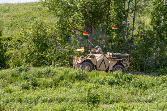 Historic military vehicle firing at Aquino Tank Weekend in Oshawa, Ontario, set against lush greenery. This annual event attracts history enthusiasts and military buffs.