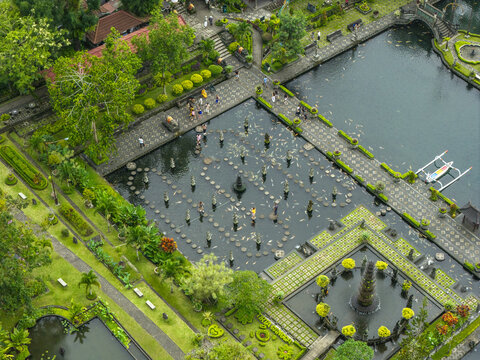 Aerial view of Tirta Gangga water palace with its iconic stepping stones, koi ponds, lush gardens, and ornate stone statues in Kecamatan Abang, Bali, Indonesia.