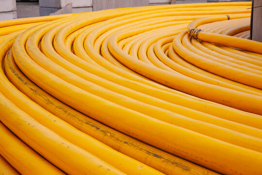 Close up view of bright yellow heavy duty underwater subsea power electric cables coiled at a port industrial terminal