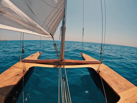 V&iacute;deo grabado desde la cubierta de un pat&iacute; catal&aacute;n navegando en mar abierto, con la vela, el m&aacute;stil y la estructura de madera en primer plano frente al horizonte. La escena transmite navegaci&oacute;n tradic