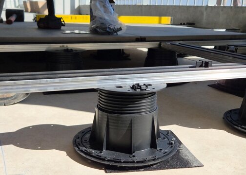 Installation of an outdoor raised flooring system using adjustable plastic pedestals and aluminum joists on a balcony or terrace.