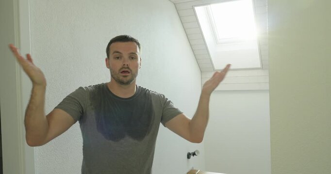 Man sweating heavily in a hot attic apartment during summer heat, showing discomfort, overheating and high temperature problems.
