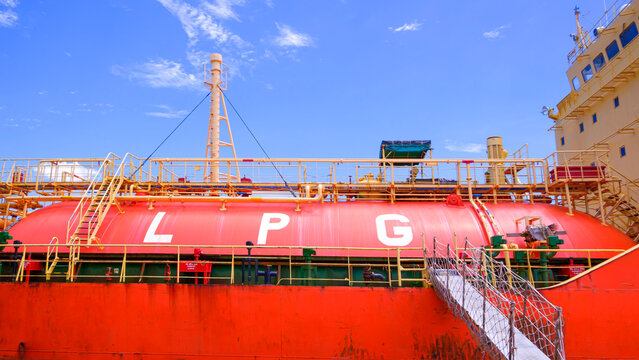 LPG gas ship tanker transport with orange fuel tank under blue sky, industrial maritime logistics and energy supply chain background
